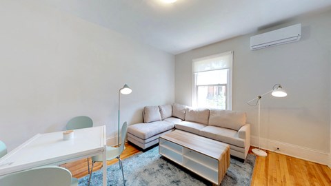 a living room with a couch and a desk and a window