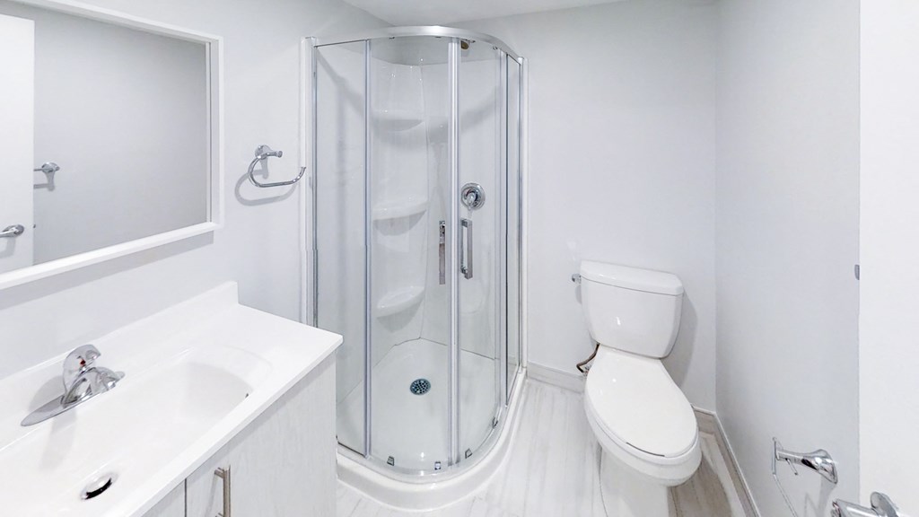a white bathroom with a shower toilet and sink