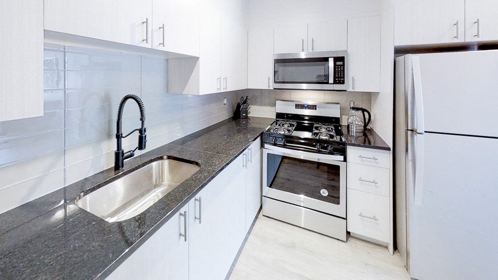a modern kitchen with stainless steel appliances and white cabinets