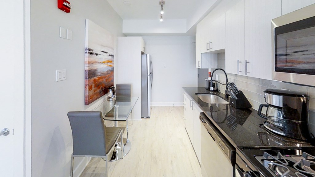 a kitchen with black counter tops and a stainless steel refrigerator