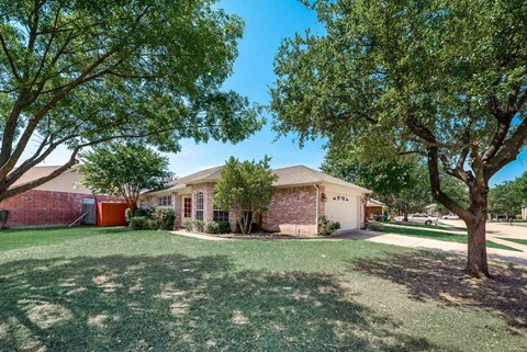 A house with a red garage door is surrounded by trees.
