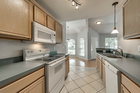 A kitchen with a white stove top oven and a microwave above it.