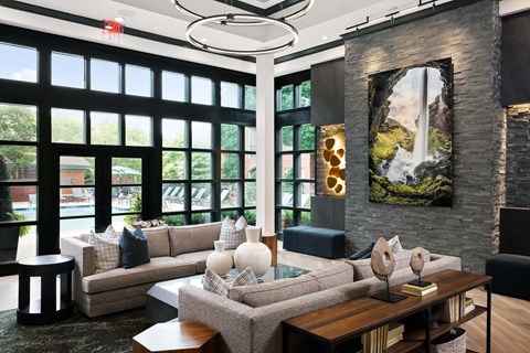 A modern living room with a large window and a painting of a waterfall on the wall.