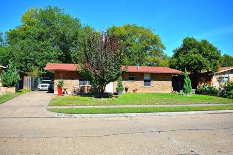 A house with a red roof and a tree in front of it.