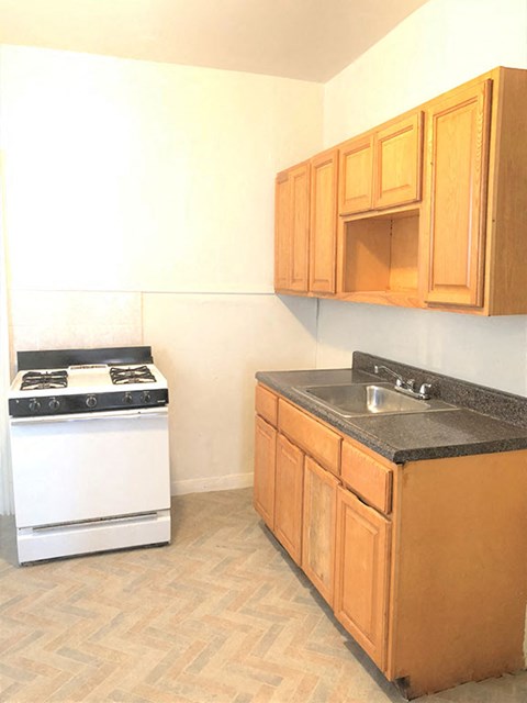 A kitchen with a white stove and wooden cabinets.