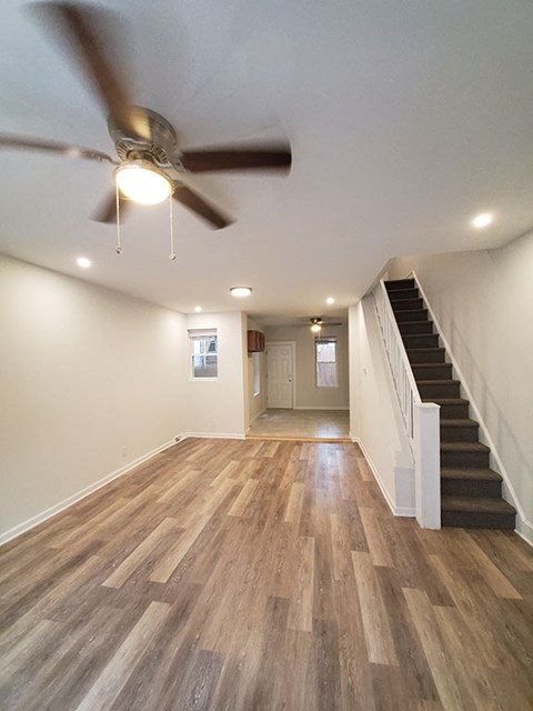 A room with a ceiling fan and wooden flooring.