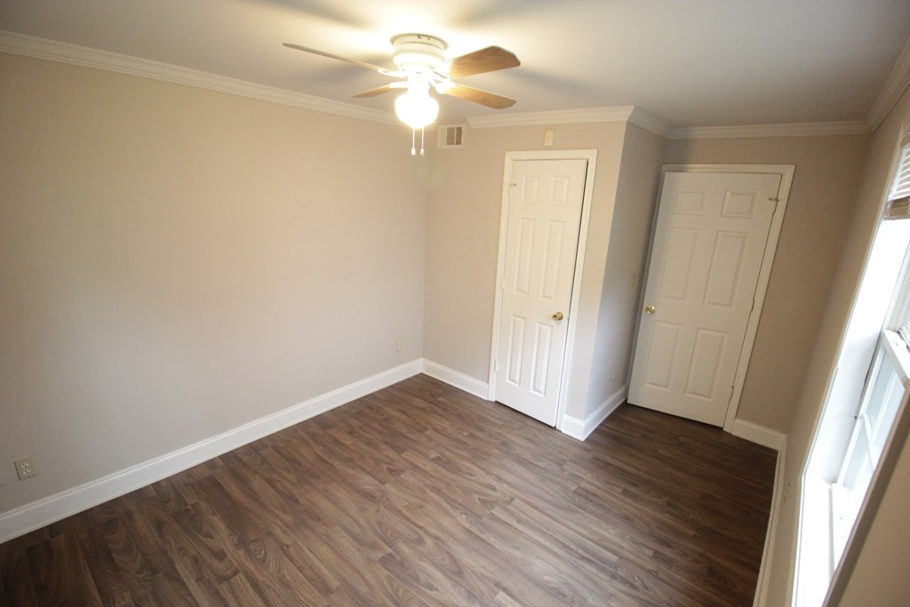 an empty living room with wooden floors and a ceiling fan