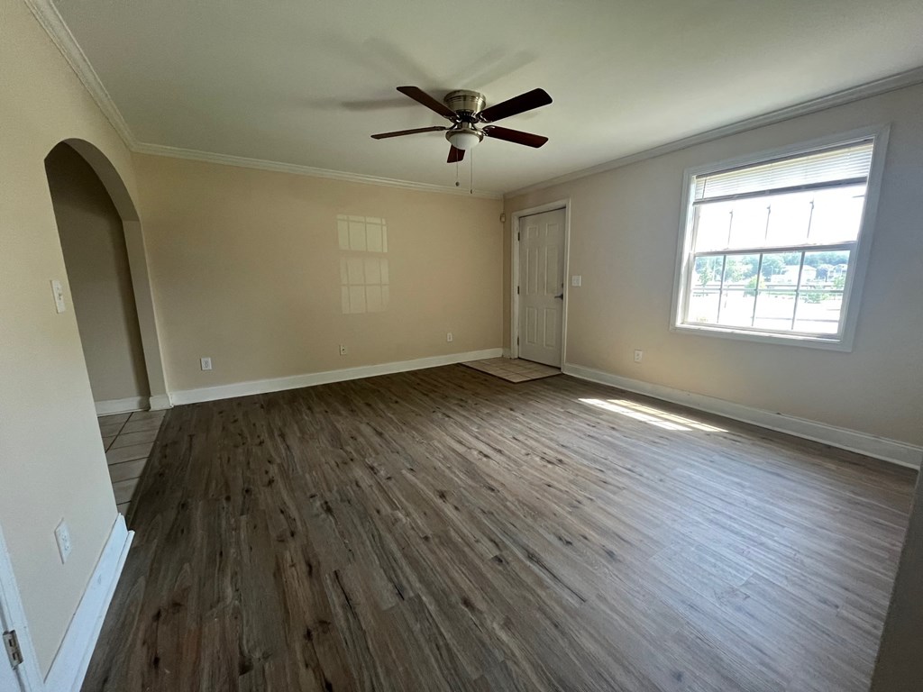 an empty living room with wooden floors and a ceiling fan