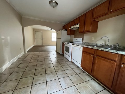 an empty kitchen with tile flooring and wooden cabinets