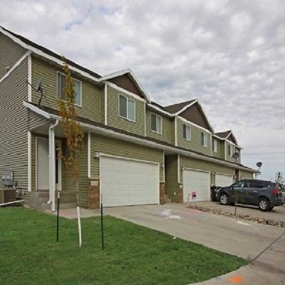 A row of houses with a car parked in front of the first one.
