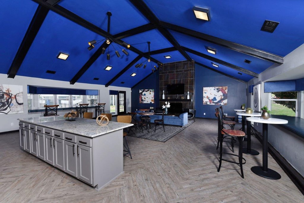 a clubhouse with a blue ceiling and a kitchen with a bar and tables