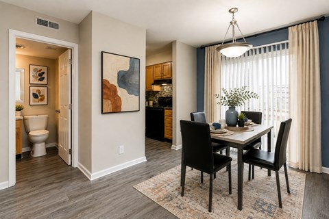 A dining room with a table set for two and a painting on the wall.