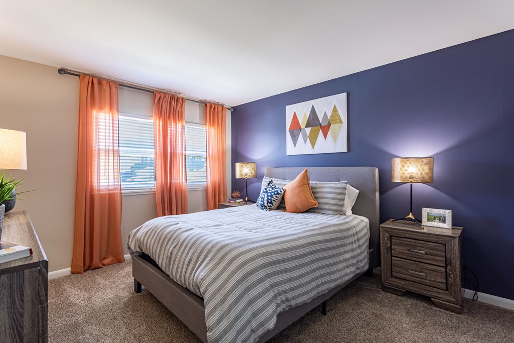 a bedroom with a bed and orange curtains