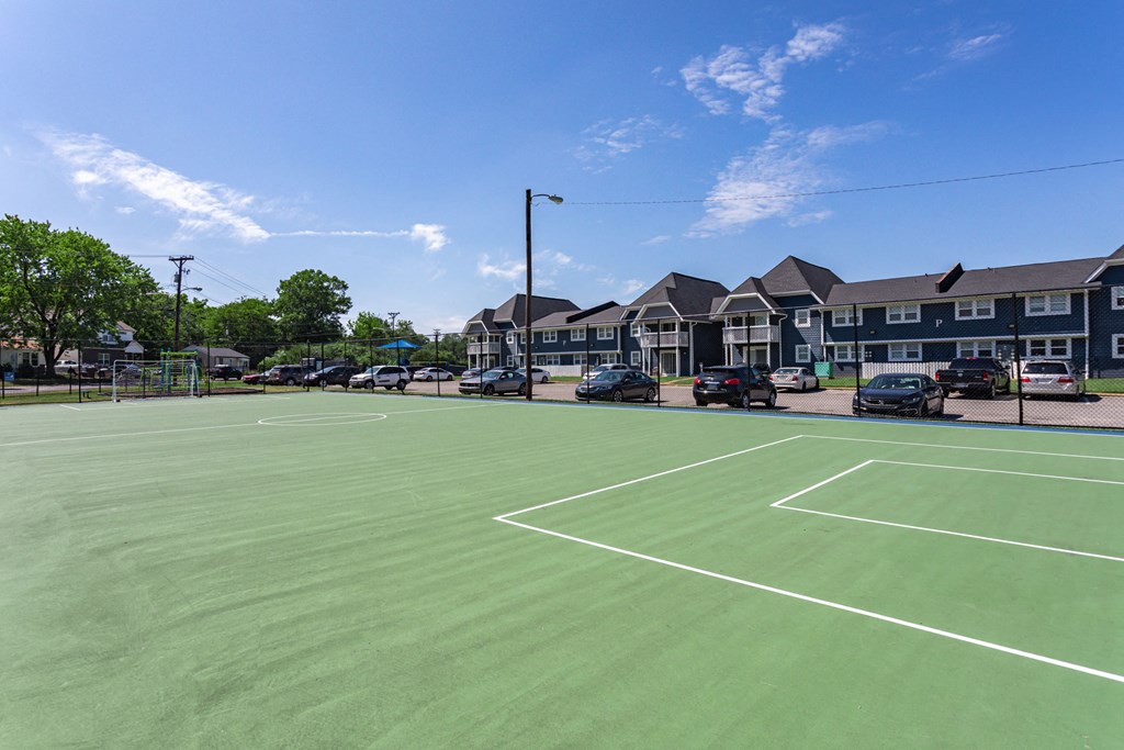 a tennis court with apartments in the background