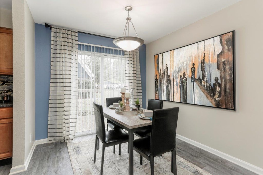a dining room with a table and chairs and a painting on the wall