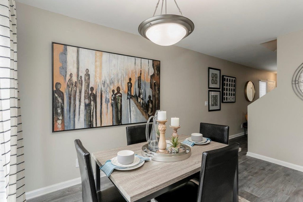 a dining room table with chairs around it and a painting on the wall