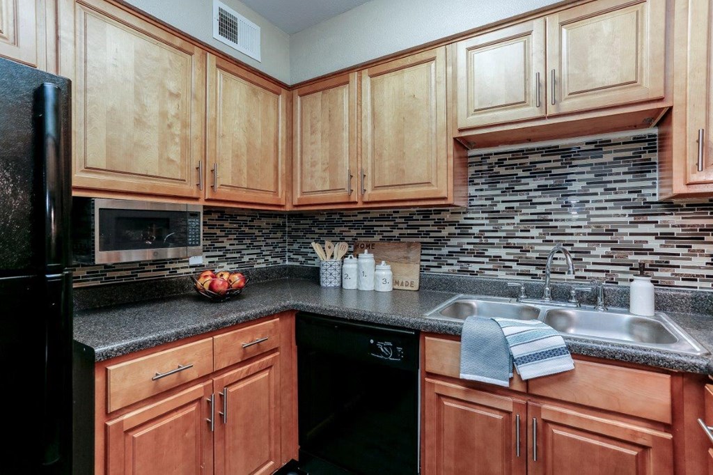 a kitchen with wooden cabinets and a black counter top
