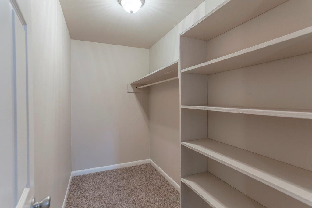 a walk in closet in a home with empty shelves