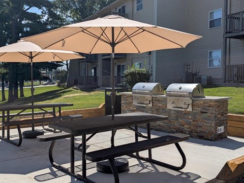 A patio with a table, chairs and umbrellas.