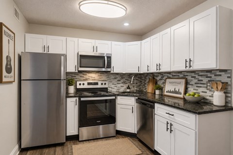 A kitchen with white cabinets and a black countertop.