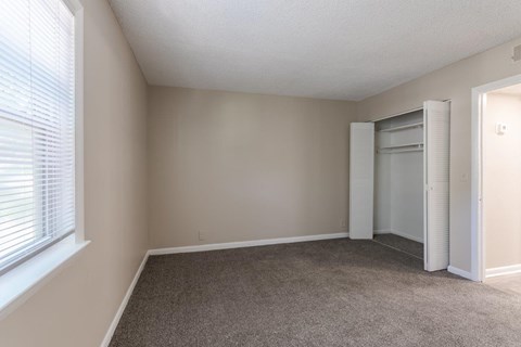 A room with a carpeted floor and a window with blinds.
