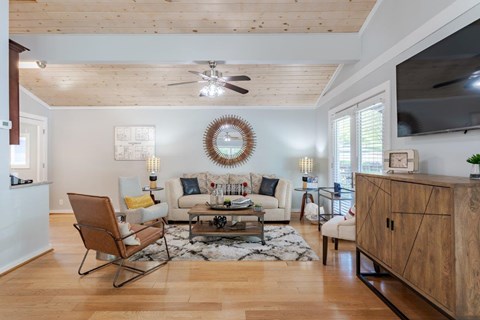 A living room with a wooden floor and a white ceiling fan.