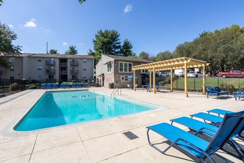 A swimming pool with sun loungers and a building in the background.