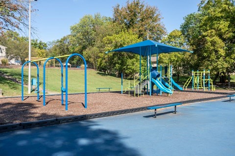 A playground with a blue umbrella and slide.