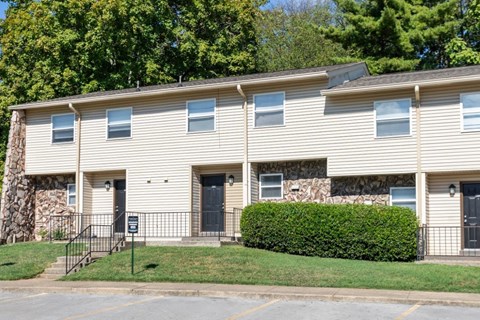 A building with a stone wall and a green hedge in front.