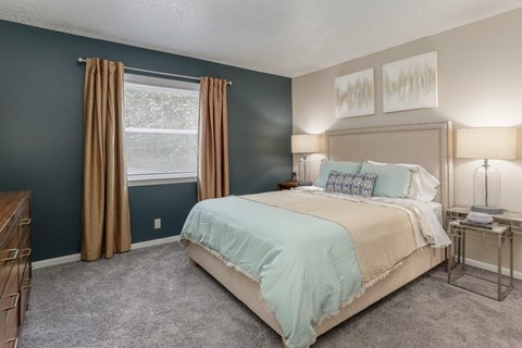 A bedroom with a bed, nightstand, and window.