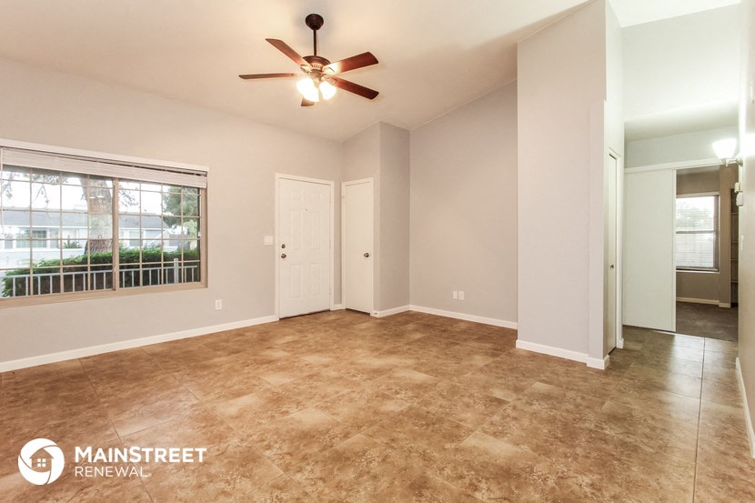 an empty living room with a ceiling fan and a window