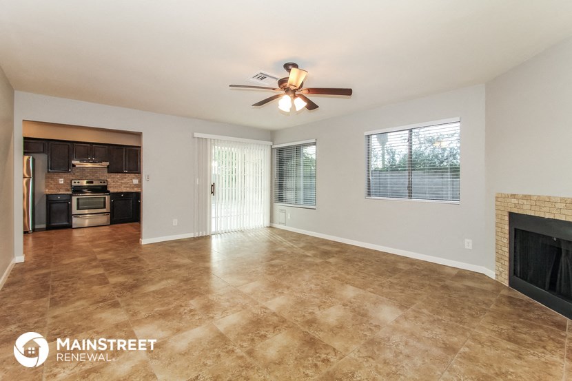 an empty living room with a fireplace and a ceiling fan