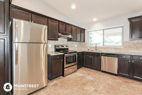 a kitchen with dark cabinets and stainless steel appliances