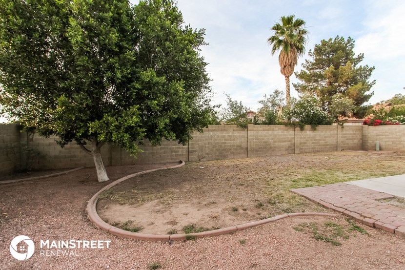 the backyard of a house with a tree and a retaining wall
