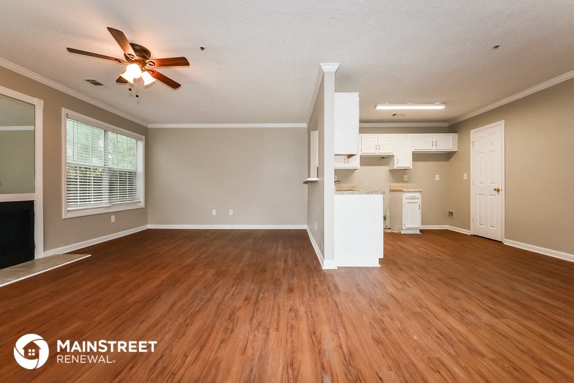 the living room and kitchen of an empty house with wood floors and a ceiling fan
