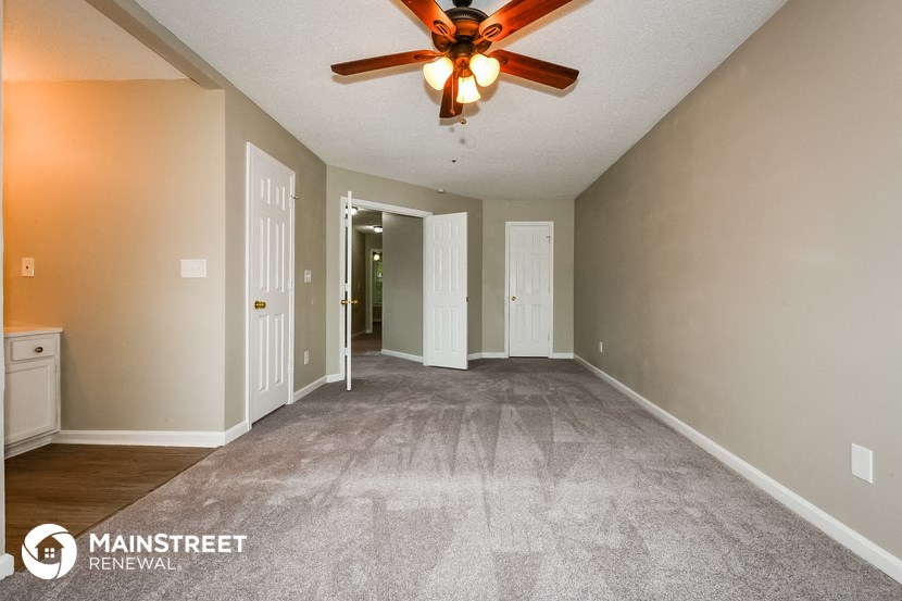 the spacious living room with carpeting and a ceiling fan