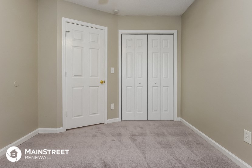 a bedroom with two doors and a carpeted floor