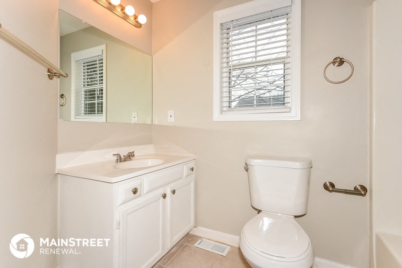 a bathroom with a toilet sink and mirror and a window