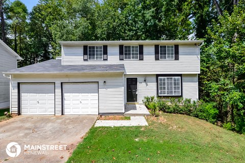 a white house with two garage doors and a lawn