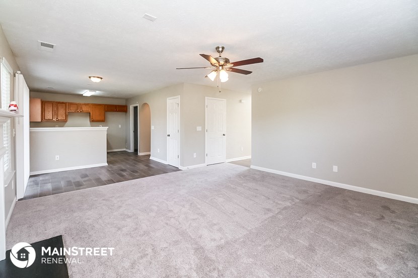 an empty living room and kitchen with a ceiling fan