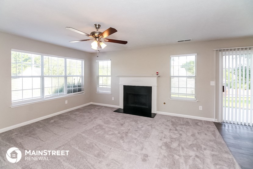 a living room with a fireplace and a ceiling fan