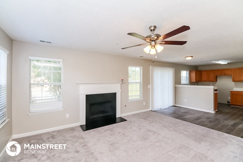 a living room with a fireplace and a ceiling fan