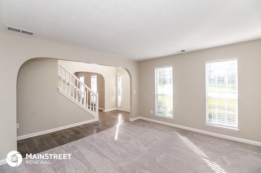 an empty living room with a staircase and windows