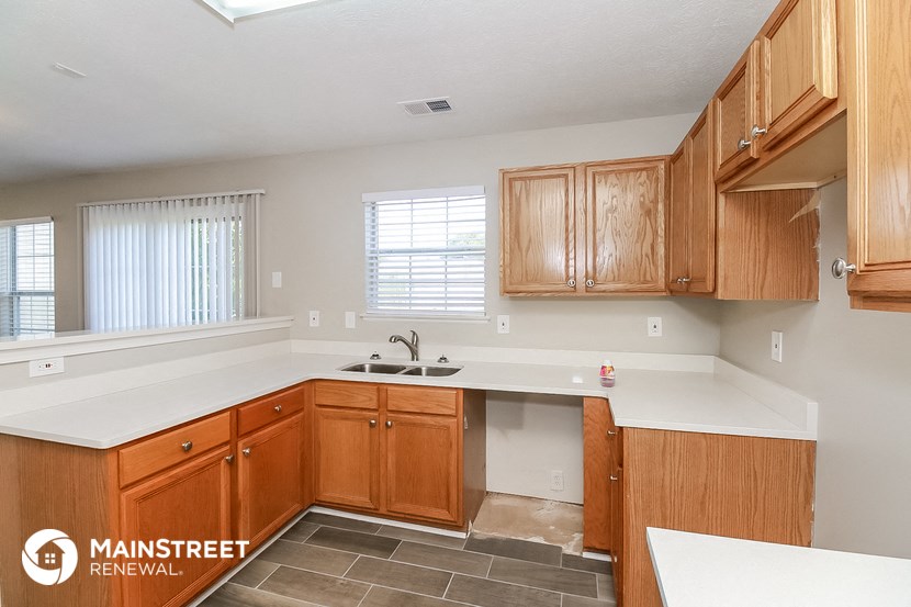 a kitchen with wooden cabinets and white counter tops and a sink