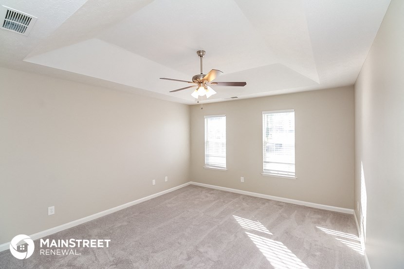 an empty living room with a ceiling fan