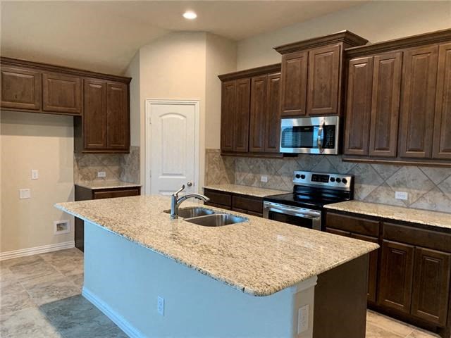 an empty kitchen with a granite counter top