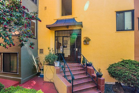A yellow house with a red staircase leading to the front door.