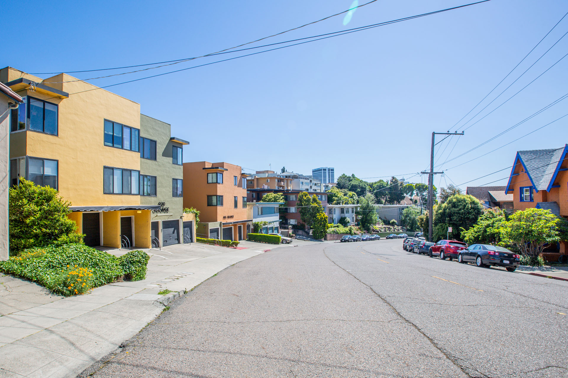 A street view of a residential area with houses and parked cars.