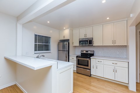 A kitchen with white cabinets and a stainless steel refrigerator.