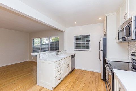 A kitchen with white cabinets and black appliances.